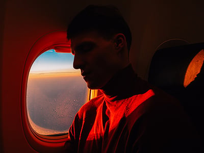 Side view of young handsome male sleeping in aircraft over window with sunset
